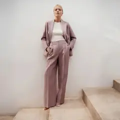 Elegancki różowy garnitur w prążki to idealna propozycja, jak się ubrać na poprawiny. Długie, szerokie spodnie i marynarka tworzą stylowy look.