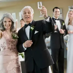 Rodzice wznoszą toast szampanem na weselu. Ich uśmiechy przypominają radosne piosenki o rodzicach.