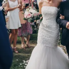 Przepiękna suknia ślubna rybka, niczym syrena, podkreśla sylwetkę panny młodej. Bukiet róż i piwonii dopełnia jej ślubny look.