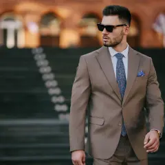 Elegancki mężczyzna w garniturze, z wzorzystym krawatem i poszetką. Czy to butonierka co to?
