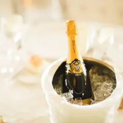 Butelka szampana Brut w wiaderku z lodem na stole weselnym.