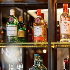 Butelki alkoholi na półce, w tym Tanqueray i Smirnoff. Idealne dla barmana na wesele, cena zależy od wyboru.