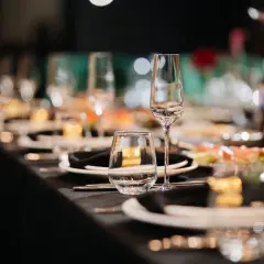 Elegancko nakryty stół weselny z kieliszkami i talerzykami. Zastanawiasz się, ile kosztuje talerzyk na weselu?
