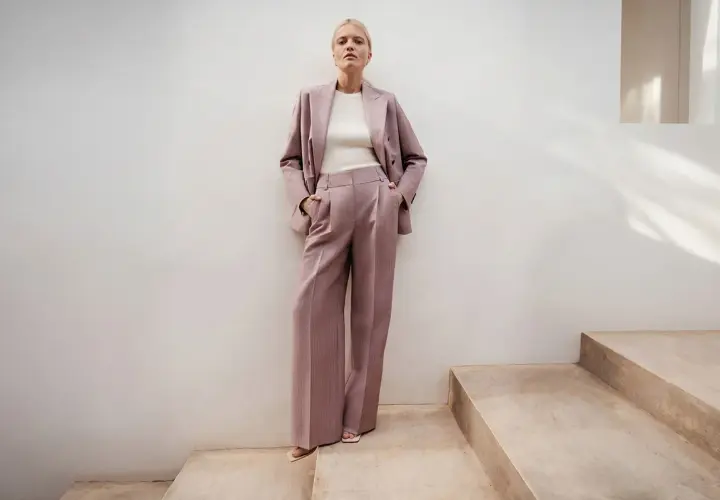 Elegancki różowy garnitur w prążki to idealna propozycja, jak się ubrać na poprawiny. Długie, szerokie spodnie i marynarka tworzą stylowy look.