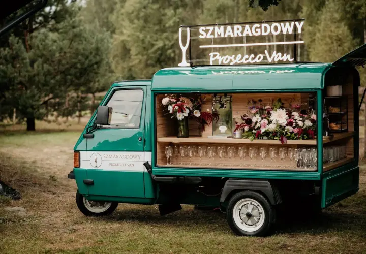 Zielony Prosecco Van "Szmaragdowy" z neonem i kwiatami, gotowy na przyjęcie.