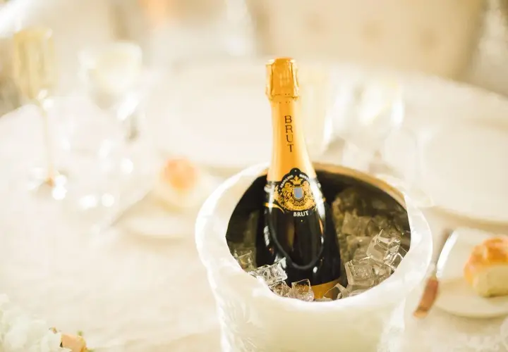 Butelka szampana Brut w wiaderku z lodem na stole weselnym.