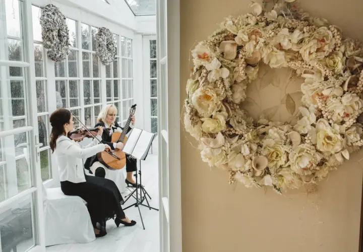 Dwie artystki grają na skrzypcach i gitarze, tworząc oprawę muzyczną ślubu. Cena takiej usługi zależy od wielu czynników.