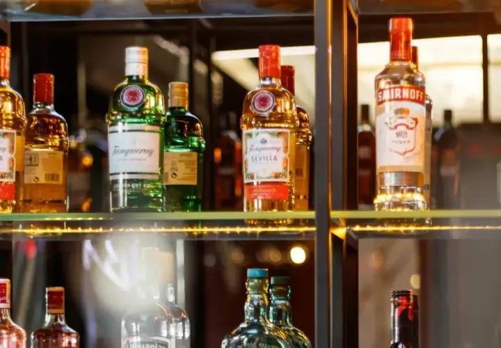 Butelki alkoholi na półce, w tym Tanqueray i Smirnoff. Idealne dla barmana na wesele, cena zależy od wyboru.