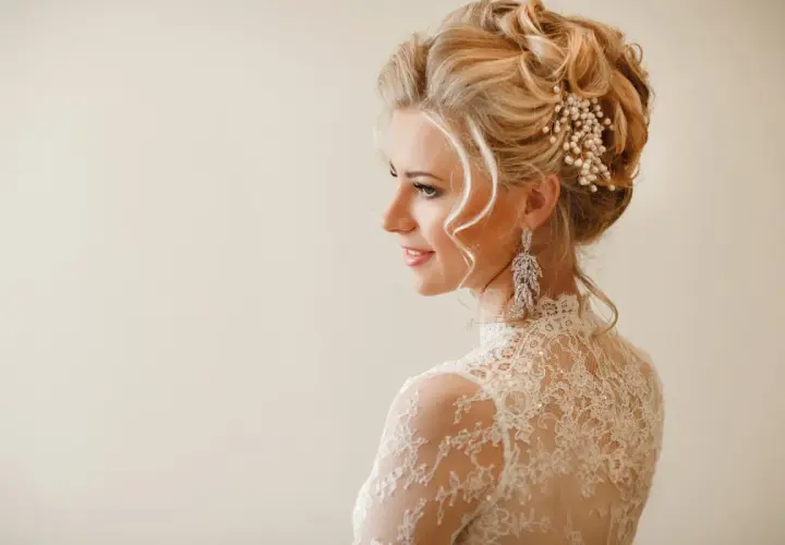 Elegancka fryzura na wesele: upięcie z perłami i długimi kolczykami. Idealna inspiracja dla panny młodej.