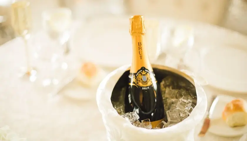 Butelka szampana Brut w wiaderku z lodem na stole weselnym.