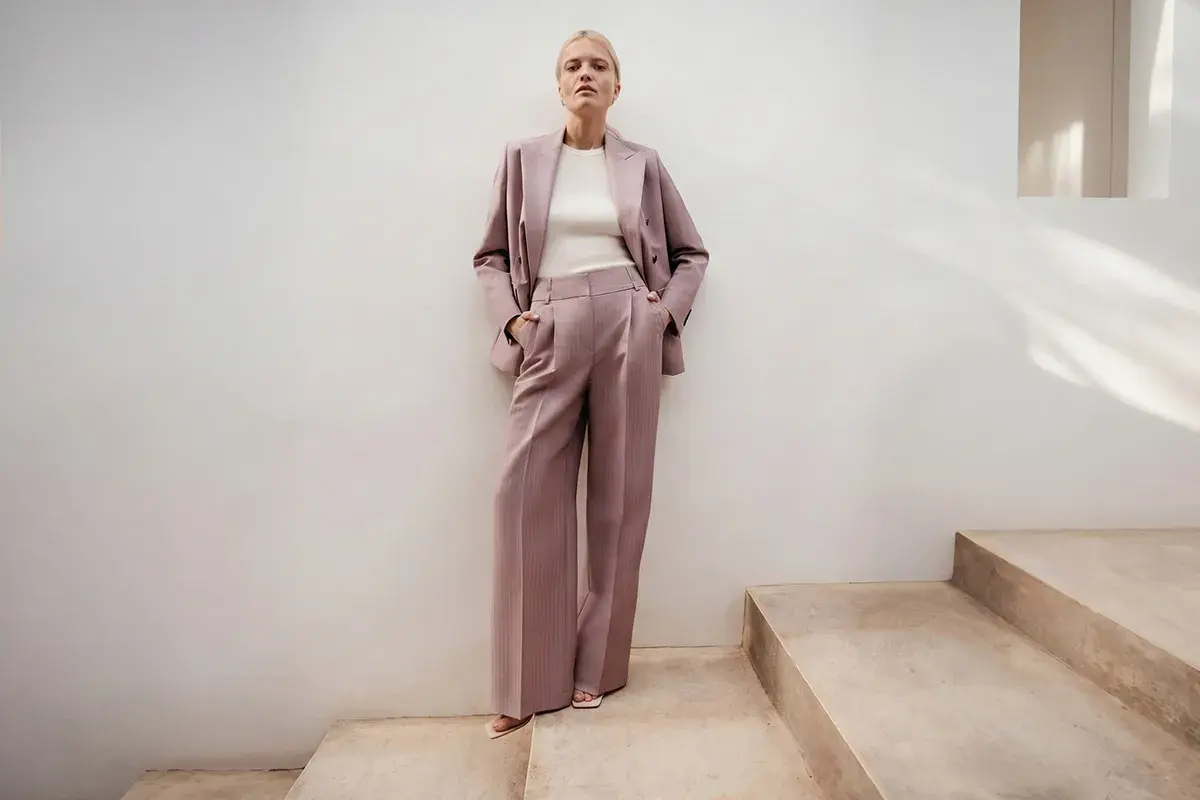 Elegancki różowy garnitur w prążki to idealna propozycja, jak się ubrać na poprawiny. Długie, szerokie spodnie i marynarka tworzą stylowy look.