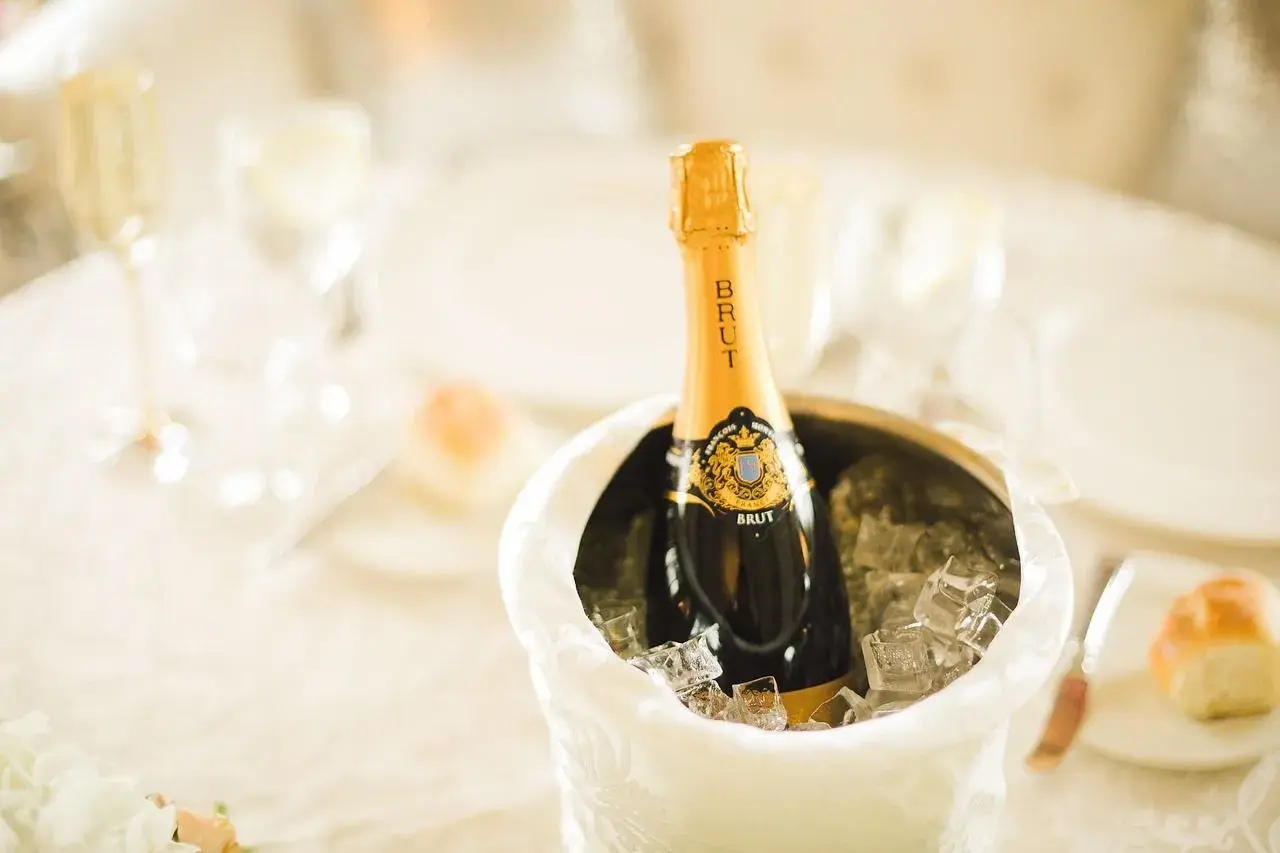 Butelka szampana Brut w wiaderku z lodem na stole weselnym.