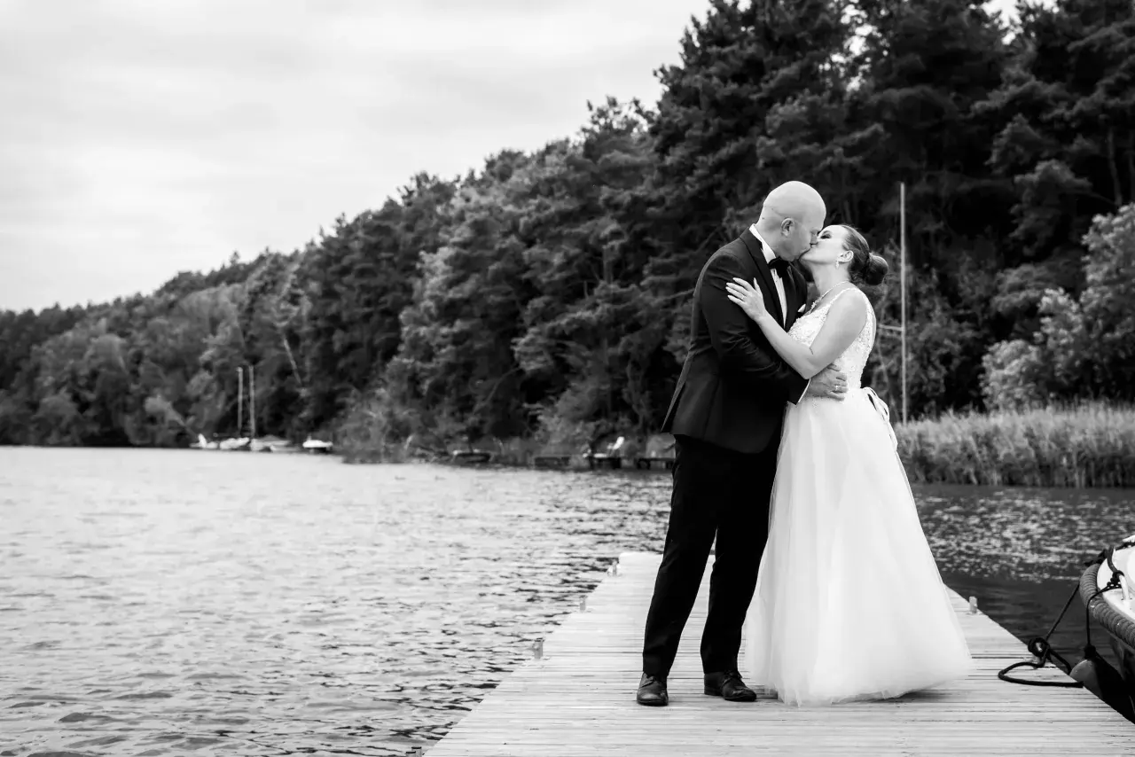 Para młoda całuje się na pomoście. Zastanawiasz się, ile kosztuje fotograf na wesele? Taka chwila warta jest uwiecznienia.