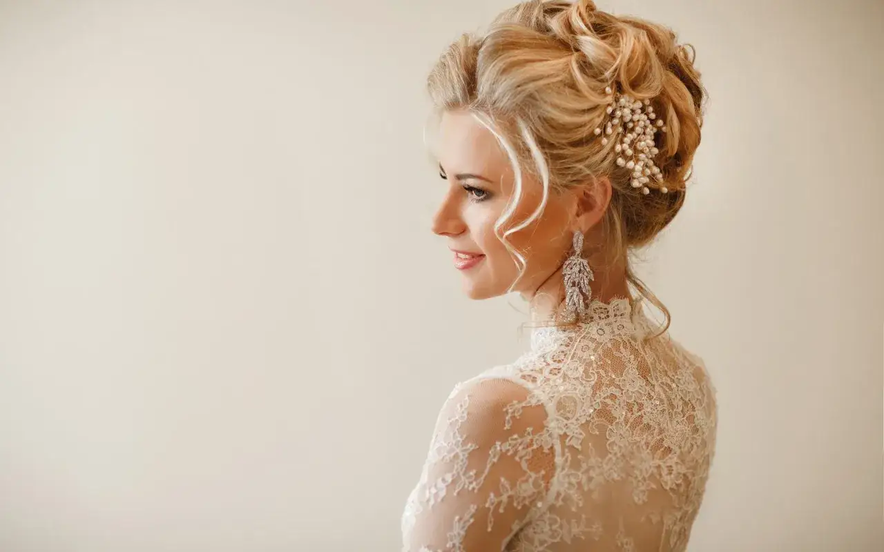 Elegancka fryzura ślubna na półdługich włosach, z perłowym zdobieniem i długimi kolczykami. Idealna na wesele.