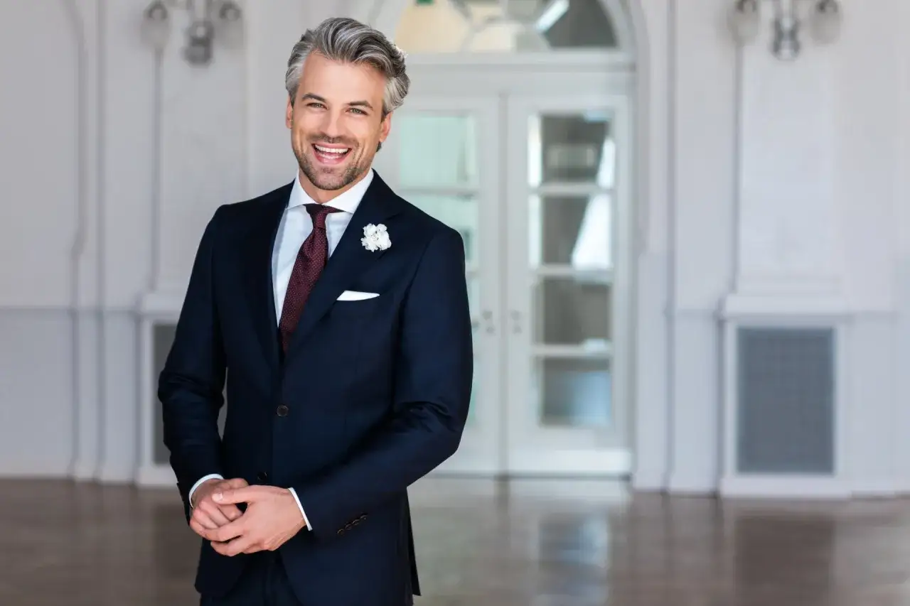 Elegancki mężczyzna w granatowym garniturze i białej koszuli, idealny wybór na wesele.