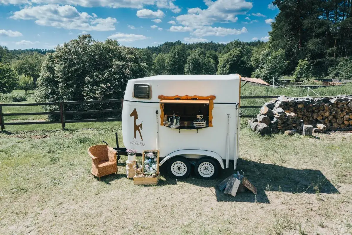 Uroczy mobilny bar na wesele w rustykalnym stylu, z koniem na boku, gotowy serwować napoje na świeżym powietrzu.