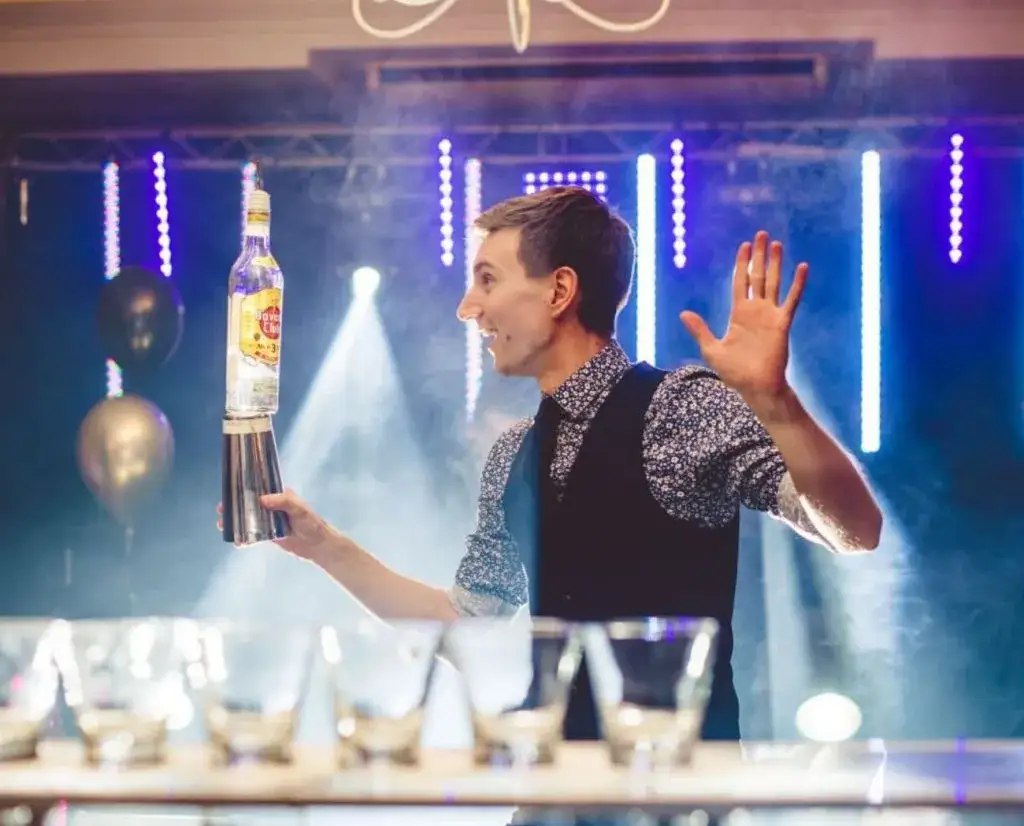elegancki barman na weselu przygotowuje kolorowe drinki