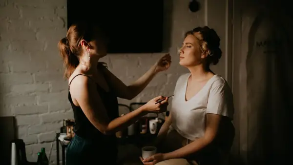 Ślub o 16, o której makijaż? Panna młoda z zamkniętymi oczami, wizażystka delikatnie nakłada jej cienie.